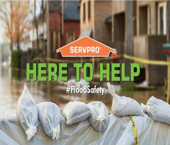 flooded home with wall of sandbags with orange SERVPRO logo