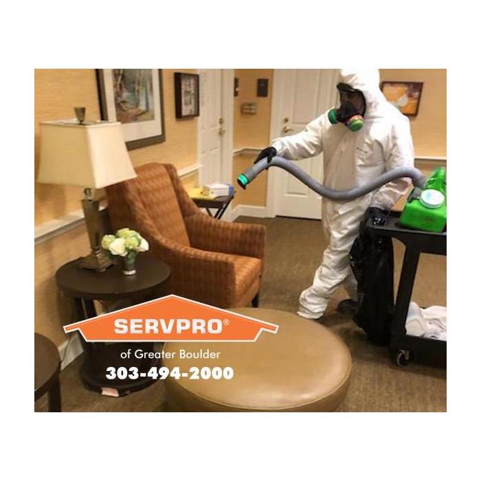 SERVPRO technician dressed in PPE cleaning a sitting room in a senior citizens home with cleaning equipment..